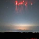 Spettri rossi a forma di medusa si librano sopra una nube temporalesca incandescente.